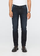 Person wearing dark blue jeans on a white background By Duer Jeans