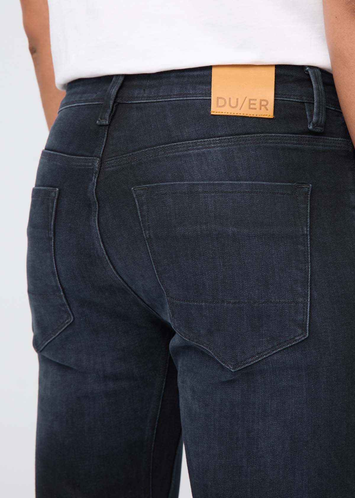 Dark jeans with a visible brand patch on a white background By Duer Jeans