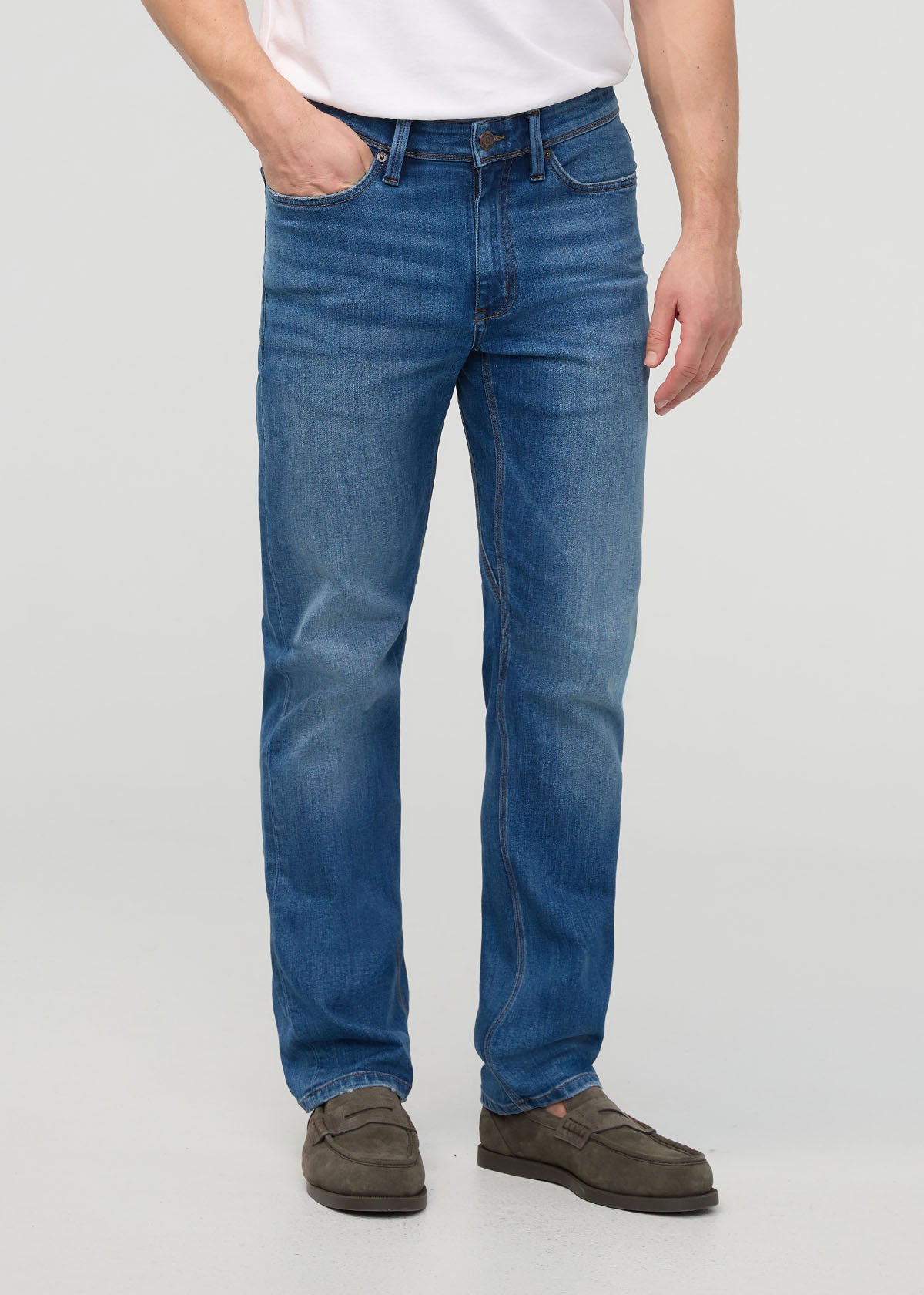Person wearing blue jeans on a plain background By Duer Jeans