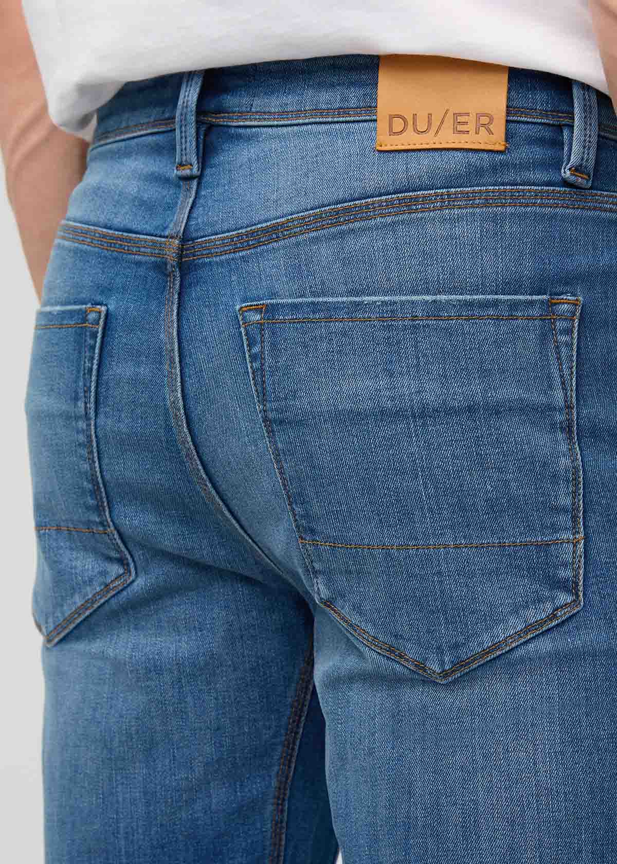 Blue jeans with a visible brand label on a light gray background By Duer Jeans