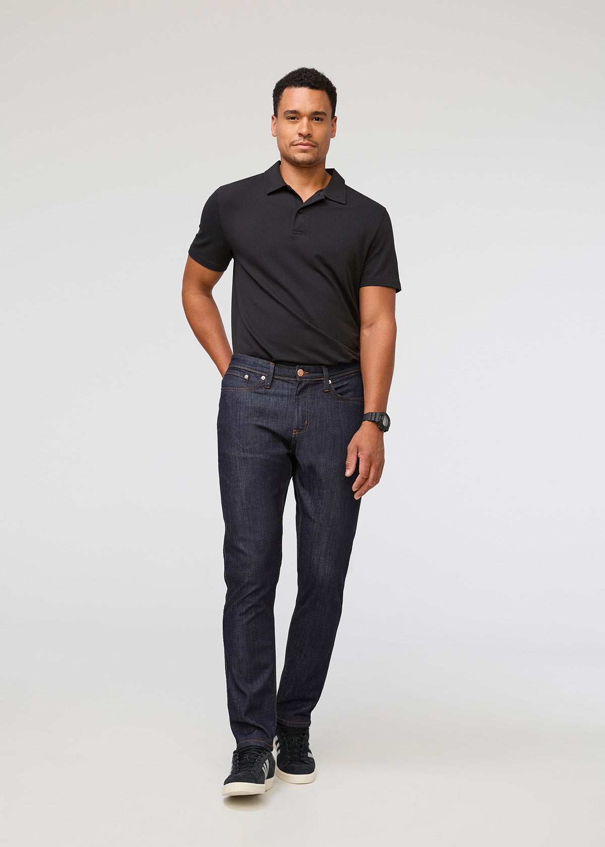 Man wearing a black polo shirt and dark jeans on a white background By Duer Jeans