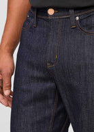 Close-up of dark blue jeans with a visible button on a light gray background By Duer Jeans