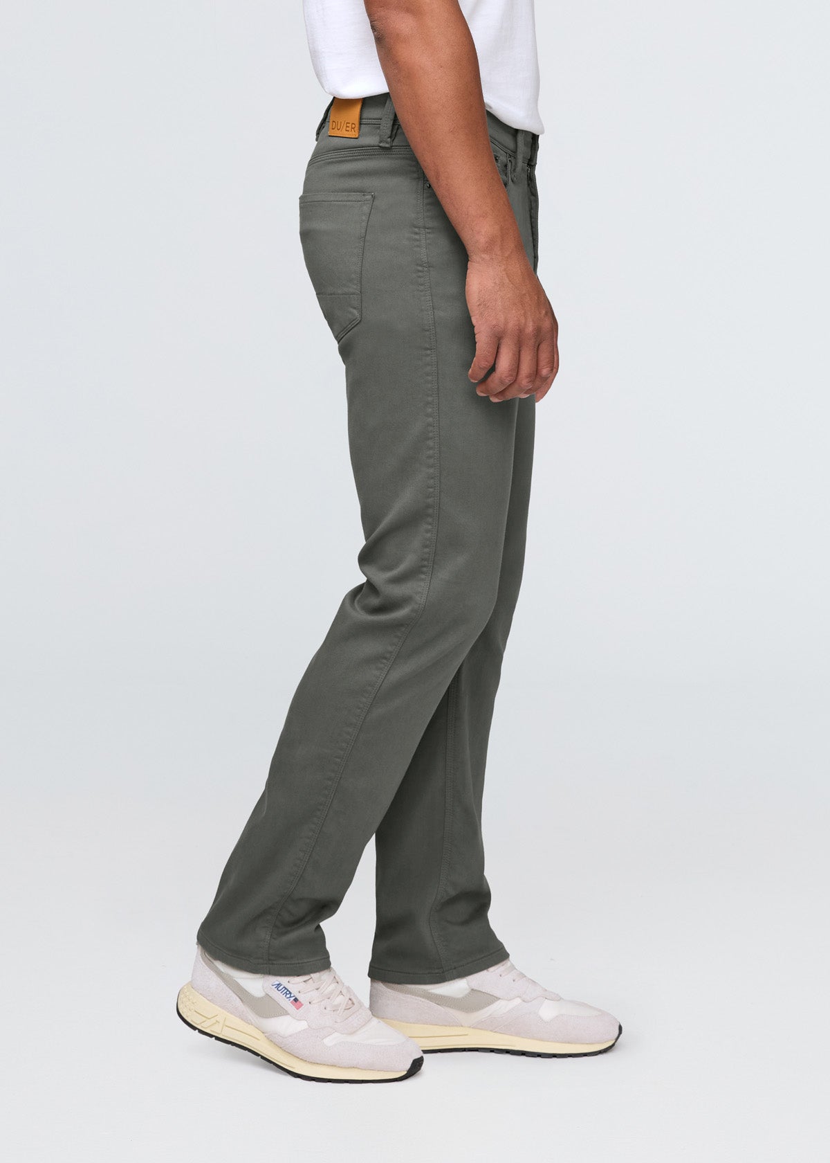Person wearing green pants and white sneakers on a plain background By Duer Jeans