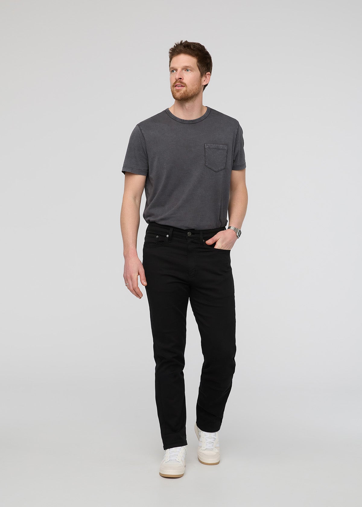 Man wearing a dark gray t-shirt and black jeans on a light gray background By Duer Jeans