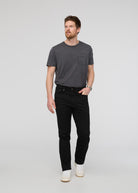 Man wearing a dark gray t-shirt and black jeans on a light gray background By Duer Jeans