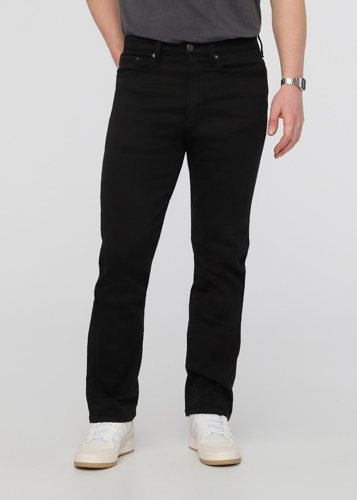 Person wearing black pants on a plain background By Duer Jeans