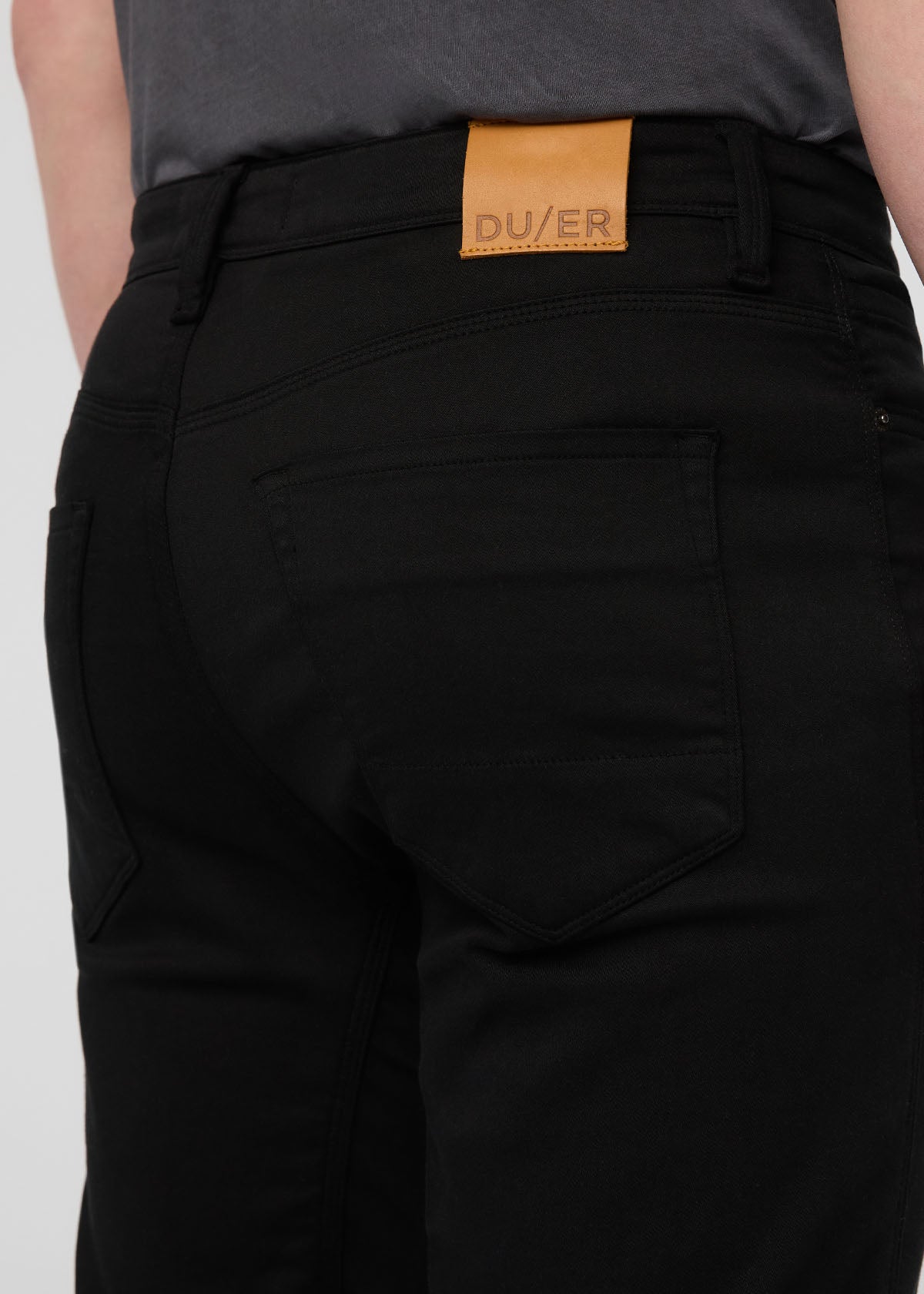 Black pants with a visible brand label on a white background By Duer Jeans