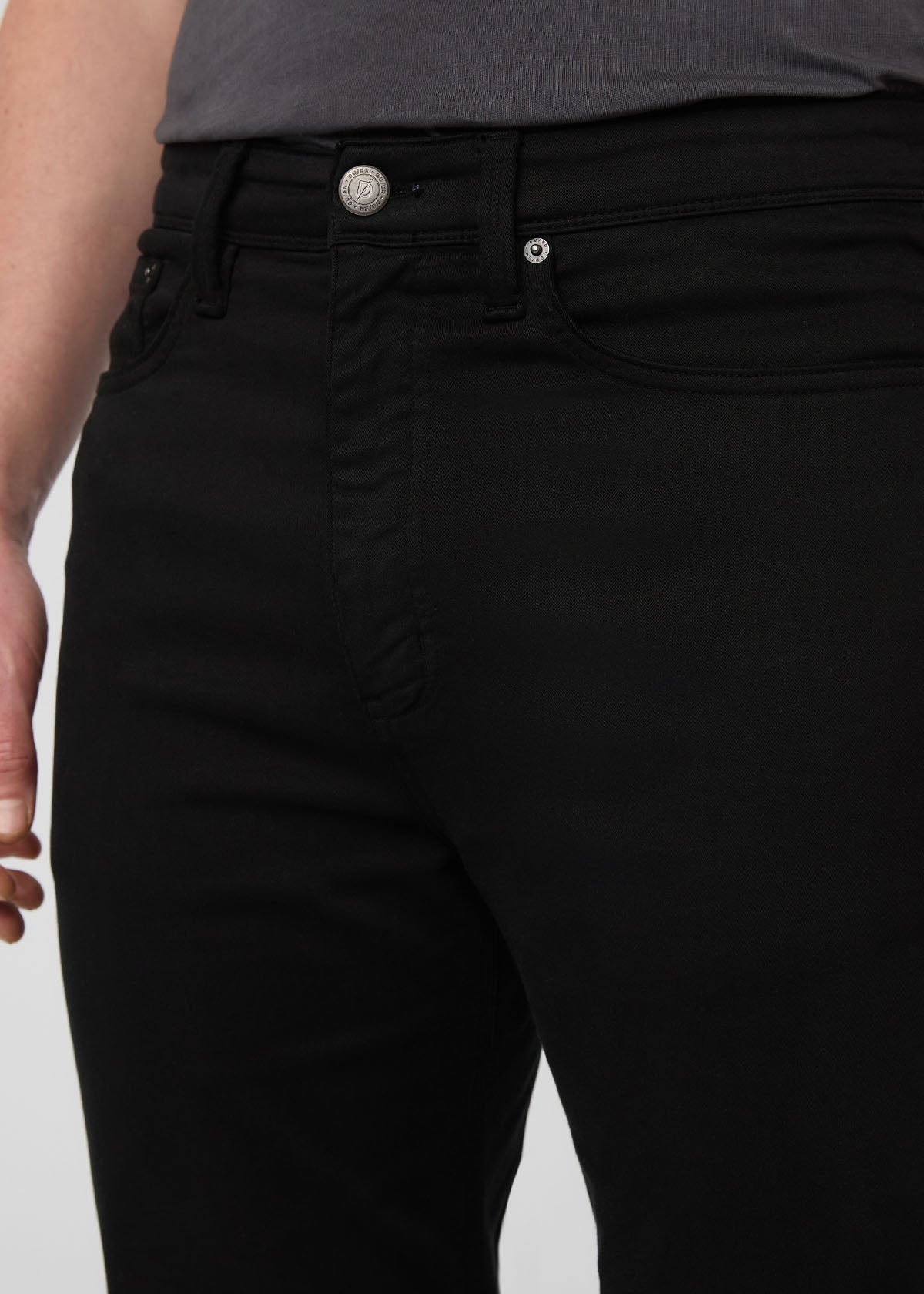 Person wearing black pants with a plain background By Duer Jeans