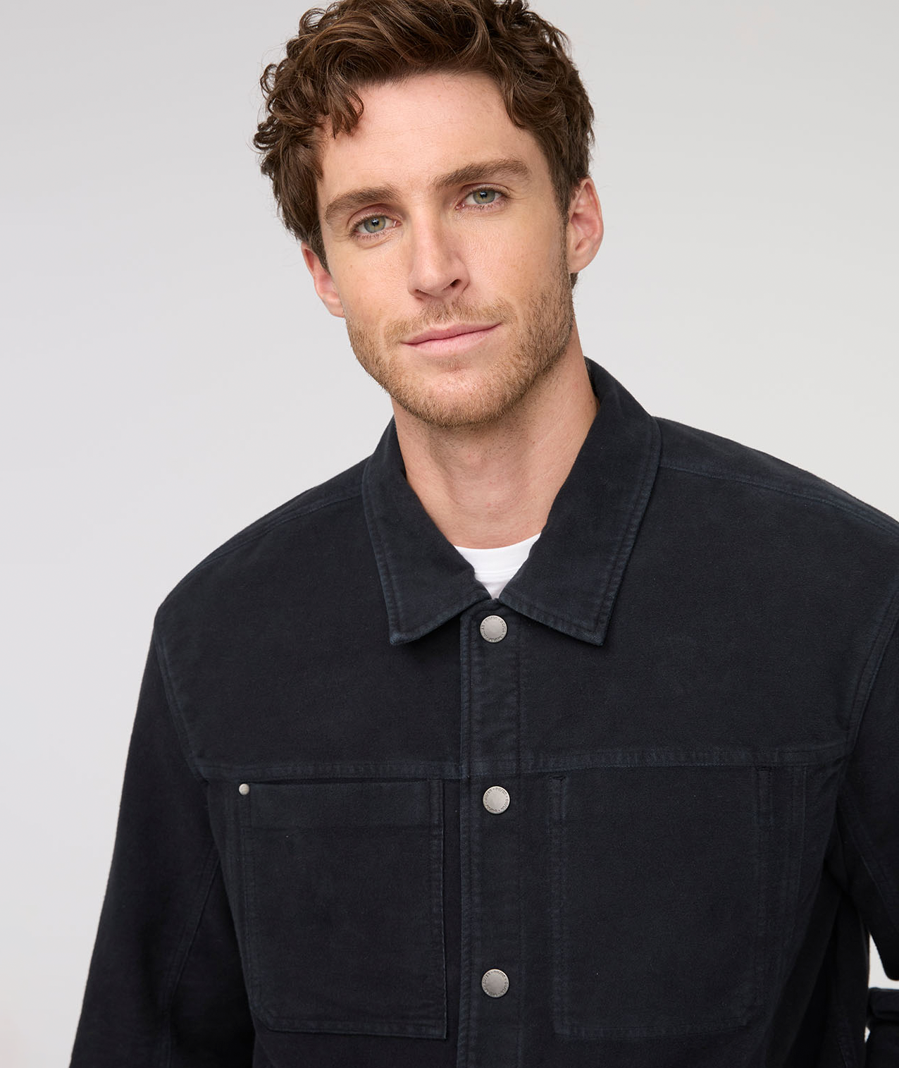 Man wearing a black jacket against a plain background By Duer Jeans
