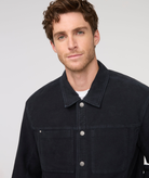 Man wearing a black jacket against a plain background By Duer Jeans
