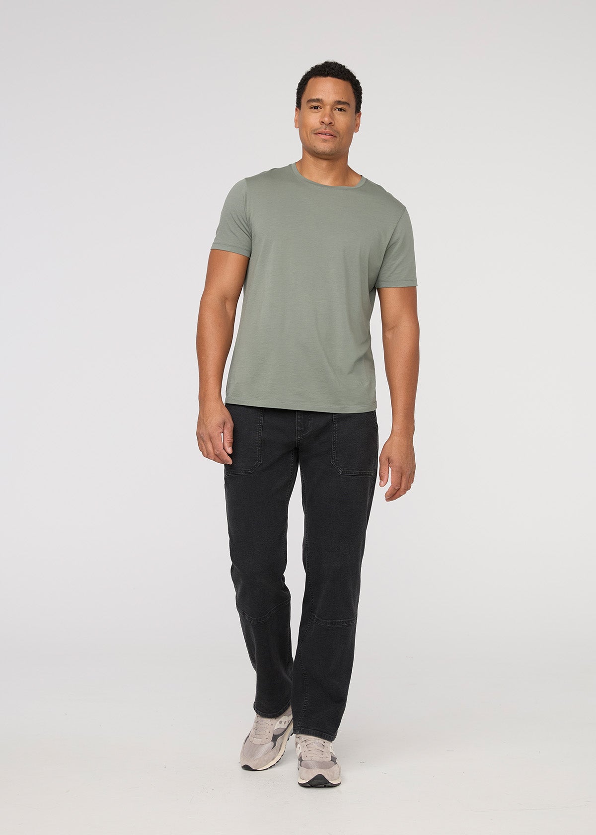 Man wearing a green t-shirt and black pants on a white background By Duer Jeans