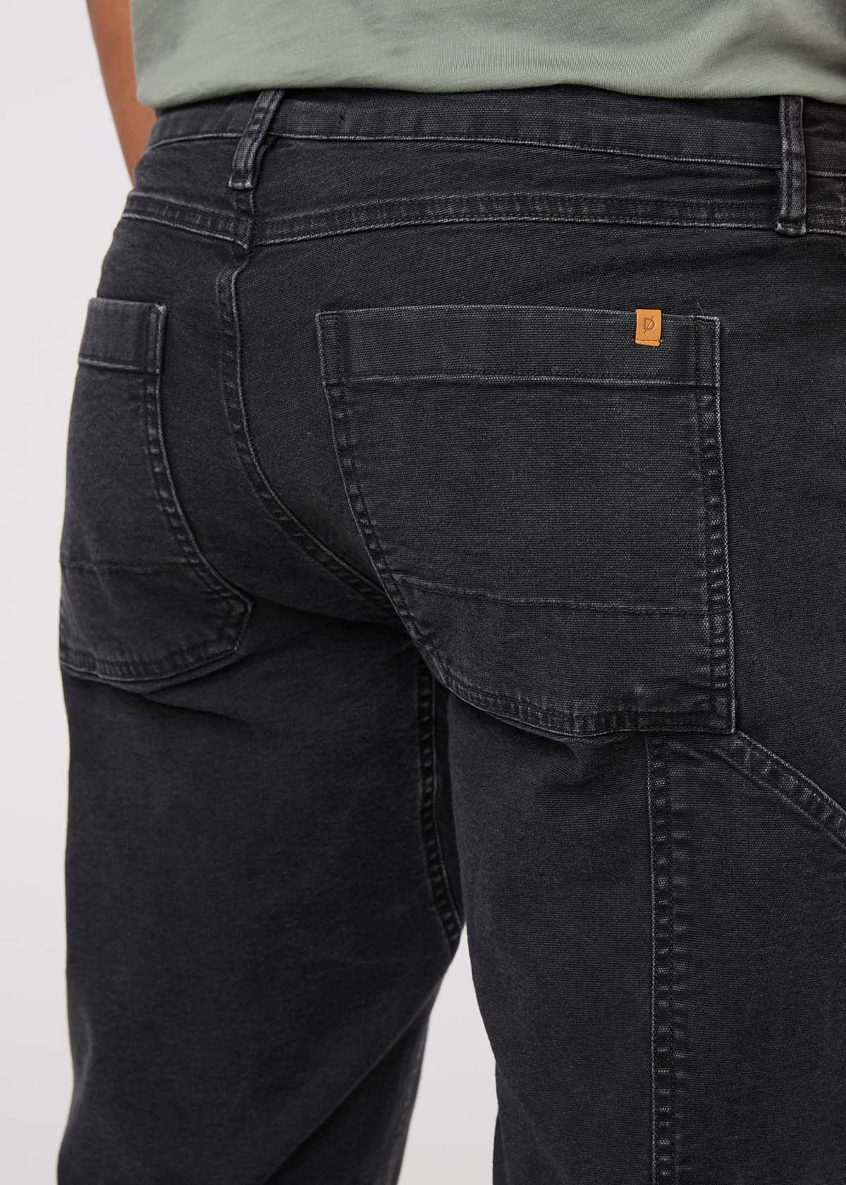 Black pants with a brand logo on the pocket against a white background By Duer Jeans