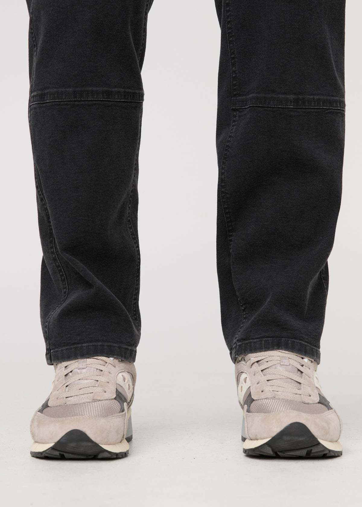 Black pants worn by a person on a white background By Duer Jeans