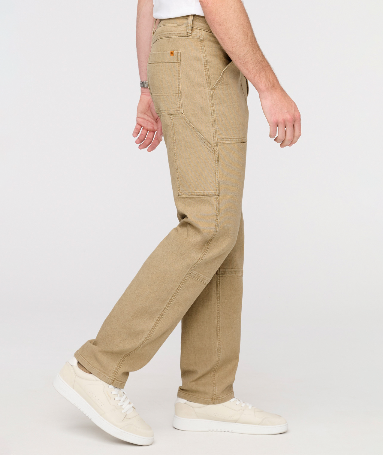 Person wearing beige cargo pants on a white background By Duer Jeans