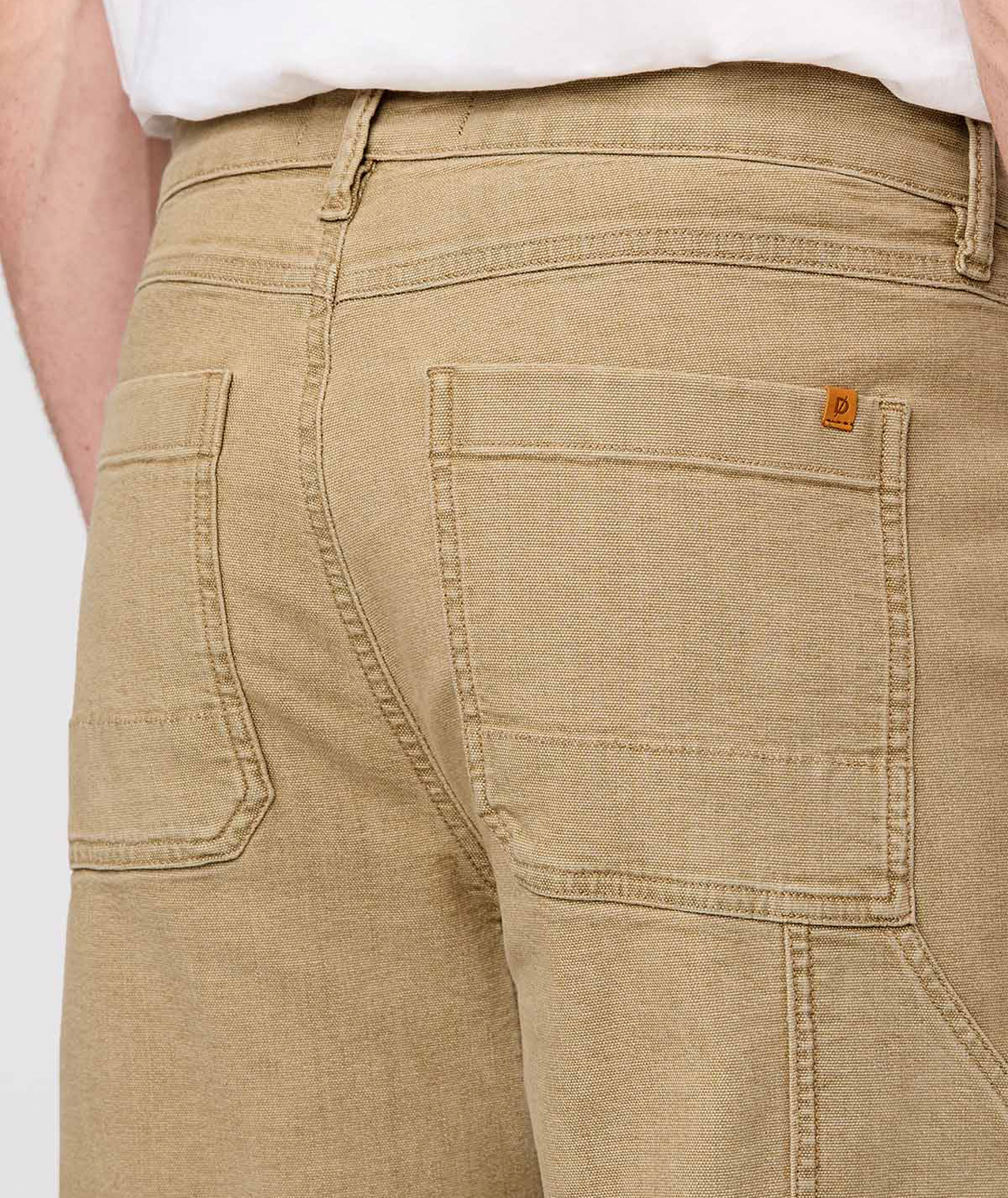 Close-up of beige pants with a brand logo on a white background By Duer Jeans