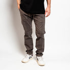 Person wearing gray checkered pants and white sneakers on a plain background By Projek Raw
